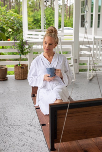 A person drinking coffee on a modern porch swing