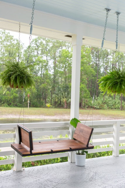 A modern porch swing with the seats facing eachother