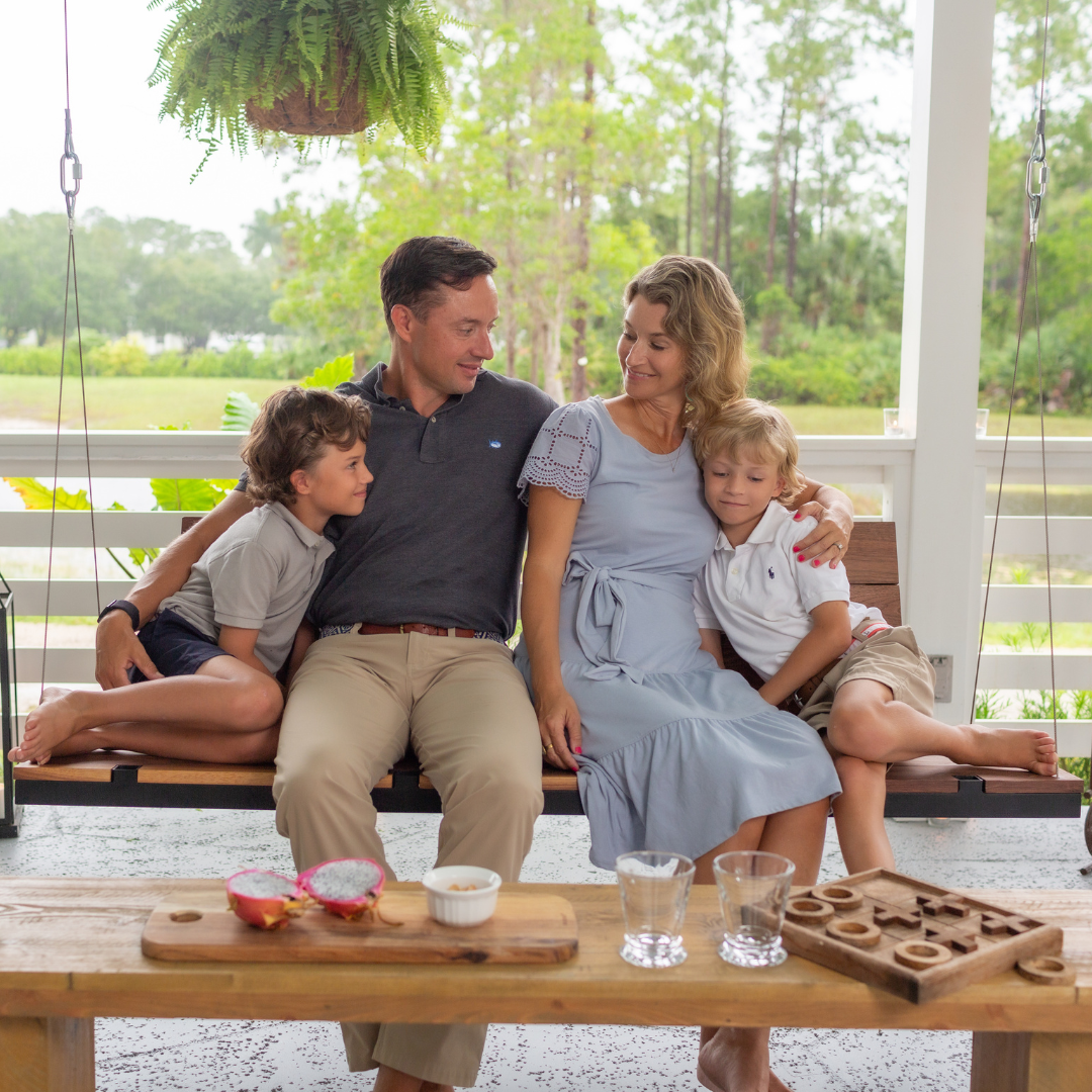 A family sitting on a modern wooden porch swing